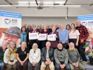 Group of Age Concern Tarnaki members holding a sign saying vote for us.